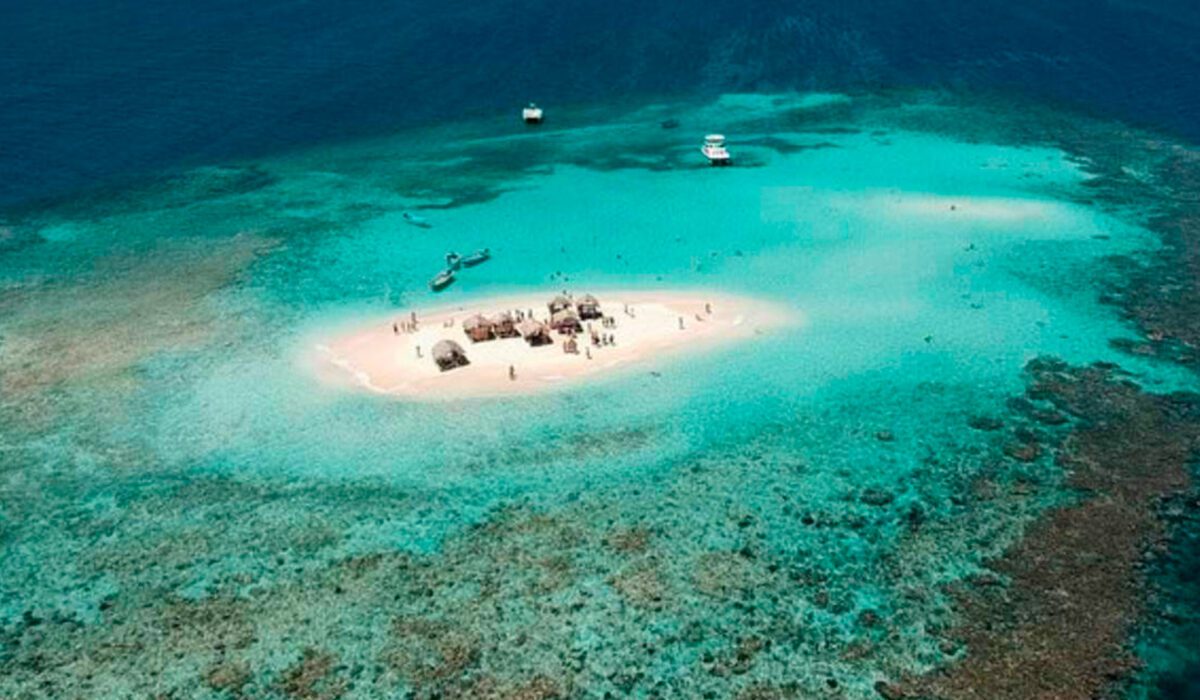 Vista aérea del banco de arena de Cayo Arena rodeado de arrecifes de coral en medio del mar.