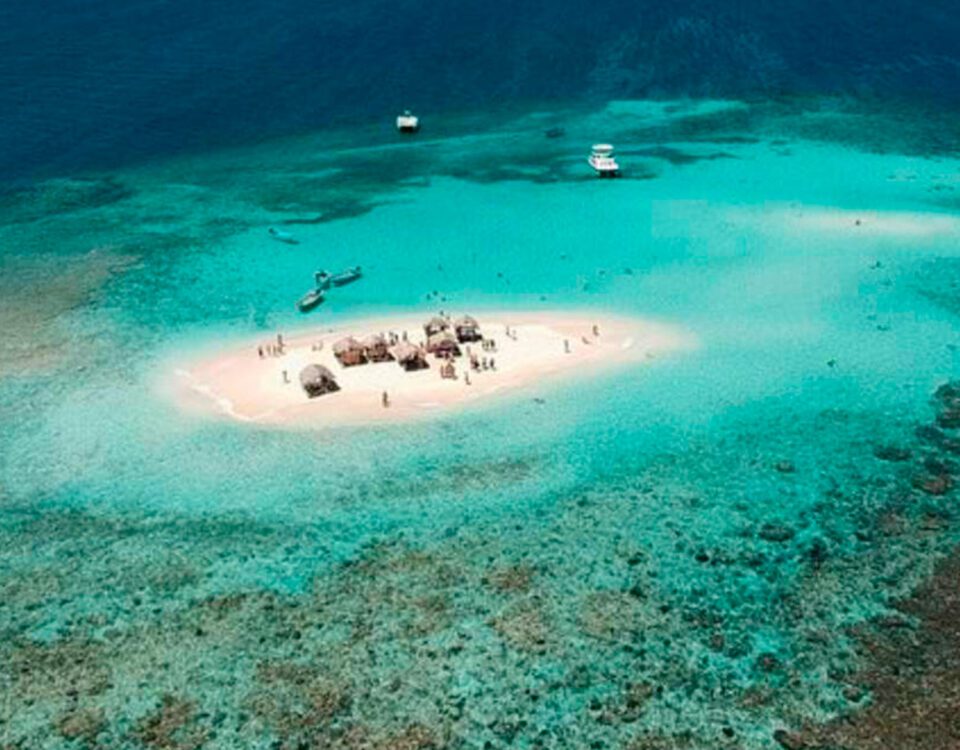 Vista aérea del banco de arena de Cayo Arena rodeado de arrecifes de coral en medio del mar.