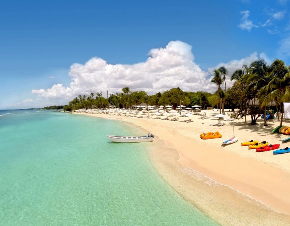Orilla de arena blanca en Playa Minitas con kayaks de colores disponibles para alquiler y aguas tranquilas color turquesa.