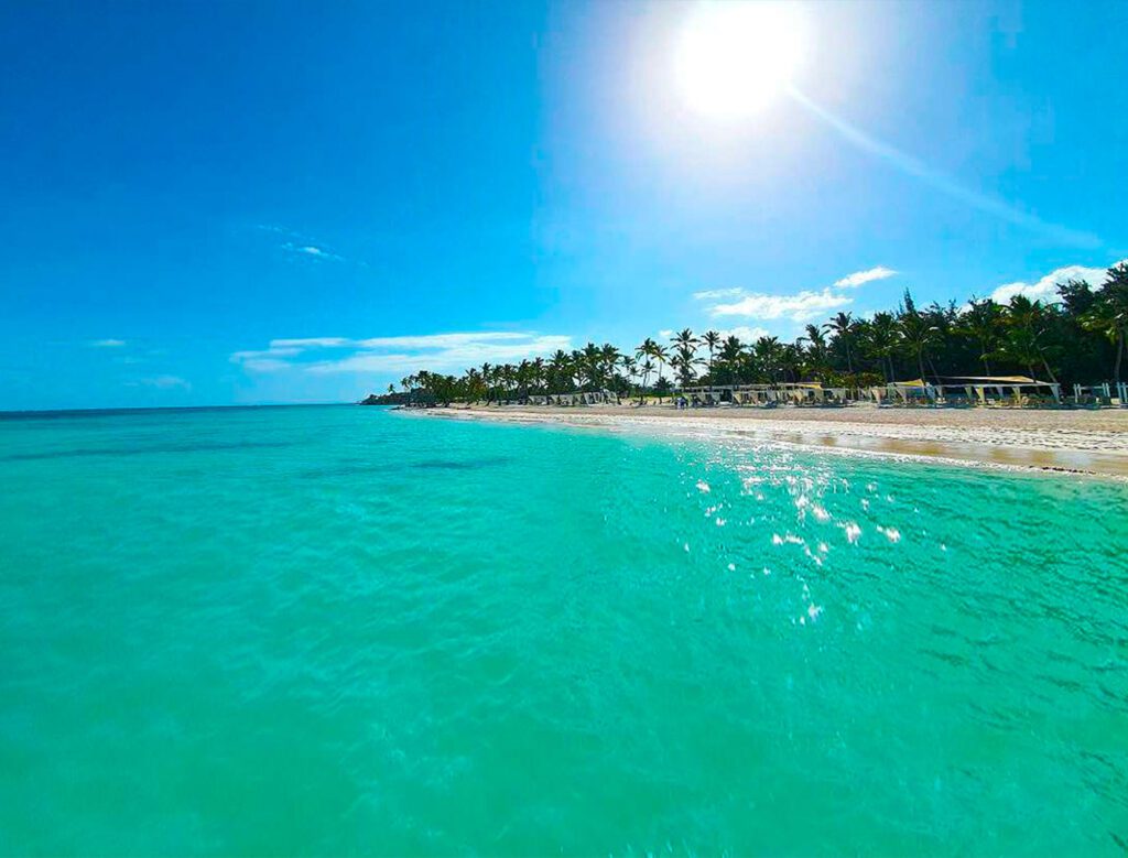 Aguas cristalinas y camas balinesas de lujo en la orilla de Playa Juanillo.